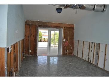 Spacious living room featuring sliding glass doors and gray tiled floors, ready for renovation at 119 18Th Nw St, Ruskin, FL 33570