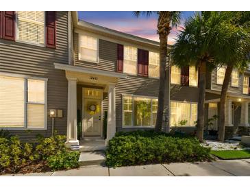 Charming townhome exterior featuring lush palm trees, red shutters, and a decorative front door at 12443 Country White Cir, Tampa, FL 33635