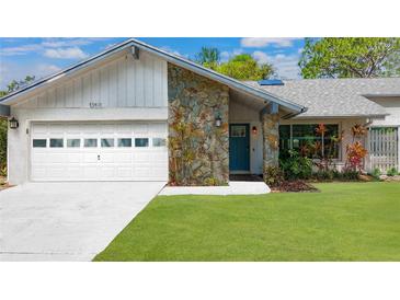 Charming home with a stone accent wall, well-maintained lawn, and a modern garage door at 13891 Feather Sound Dr, Clearwater, FL 33762