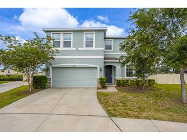 Two-story home with a two car garage, blue exterior paint, and well-maintained landscaping at 16633 Goose Ribbon Pl, Wimauma, FL 33598