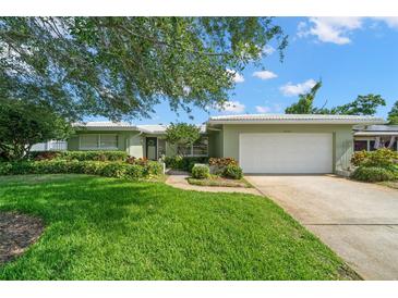Charming single-story home with a well-manicured lawn, mature trees, and a two-car garage at 2060 Attache Ct, Clearwater, FL 33764