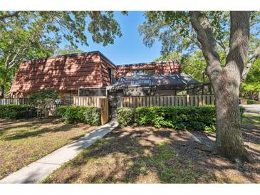 Charming condo with a brick exterior, red tile roof, and a lovely fenced front yard with mature landscaping at 2722 11Th Ct # 50A, Palm Harbor, FL 34684