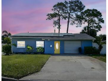 Charming single-story blue home featuring solar panels, a yellow front door, and a well-maintained front yard at 4511 Huntington Ne St, St Petersburg, FL 33703