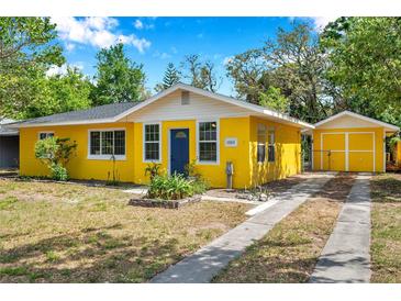 Charming yellow house with a blue door and well-maintained front yard at 1665 Laura St, Clearwater, FL 33755
