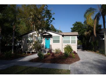 Charming single-story home featuring a bright turquoise door, manicured landscaping, and a brick paved walkway and driveway at 1914 53Rd S St, Gulfport, FL 33707