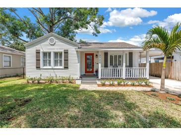 Charming single-story home featuring a red front door, white picket fence, and a well-manicured lawn at 3709 W Santiago St, Tampa, FL 33629