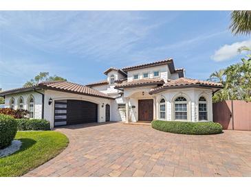 Stunning two-story home with a terracotta tile roof, brick driveway, and beautiful landscaping at 3931 Pompano Se Dr, St Petersburg, FL 33705