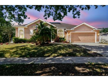 Charming single-story home with a well-manicured lawn, two-car garage, and beautiful landscaping at 1939 Heartland Cir, Valrico, FL 33594