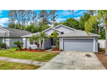 Charming single-story home featuring a well-manicured lawn, mature trees, and a two-car garage at 5143 New Brittany Ln, Zephyrhills, FL 33541