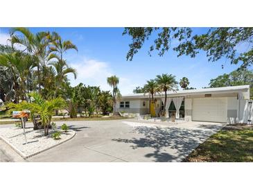 Charming single-story home featuring a well-manicured lawn and tropical landscaping with a light grey painted exterior at 8347 41St N Ave, St Petersburg, FL 33709