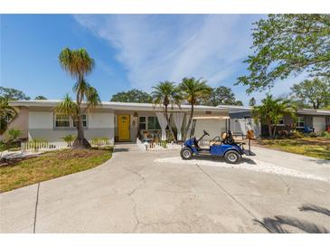 Attractive single-story home with a well-kept lawn and driveway, accented by lush landscaping and a yellow front door at 8347 41St N Ave, St Petersburg, FL 33709