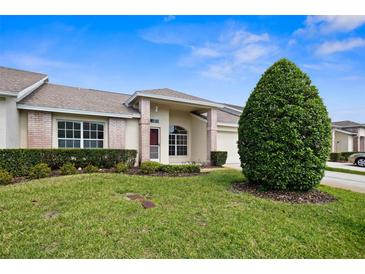Charming single-story home featuring a well-manicured lawn, complemented by lush green bushes and a brick entryway at 1046 Almondwood Dr, Trinity, FL 34655