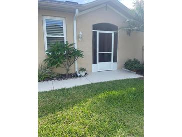 Charming front entrance with a screened door, mature landscaping, and neutral exterior at 2007 Acadia Greens Dr # 0, Sun City Center, FL 33573
