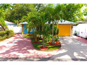 Charming home with lush palm trees, bright yellow garage door, and a colorful brick driveway at 3306 E Chelsea St, Tampa, FL 33610