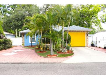 Charming blue home featuring well-manicured landscaping and a bright yellow garage door at 3306 E Chelsea St, Tampa, FL 33610