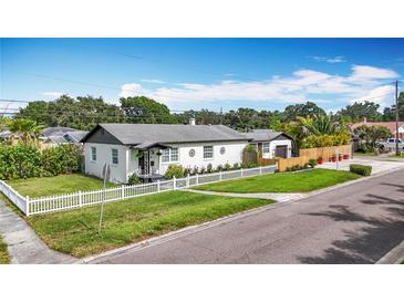 Charming single-story home with a white picket fence and well-manicured lawn under a bright blue sky at 4231 8Th N St, St Petersburg, FL 33703