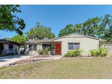 Charming single-story home featuring a well-maintained lawn and a vibrant, inviting front door at 4425 W Bay Villa Ave, Tampa, FL 33611