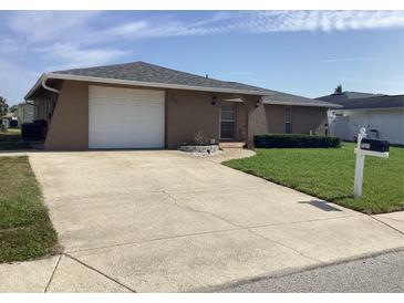 Charming single-story home featuring a two-car garage, manicured lawn, and a welcoming front entrance at 7321 Isle Dr, Port Richey, FL 34668