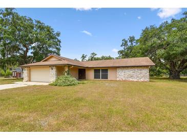 Ranch-style home with stone accents, attached garage, and well-maintained front lawn at 5306 Downing St, Dover, FL 33527