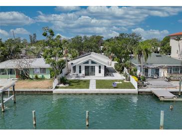 Charming waterfront home featuring a manicured lawn, waterfront access, and an inviting exterior at 8635 Boca Ciega Dr, St Pete Beach, FL 33706