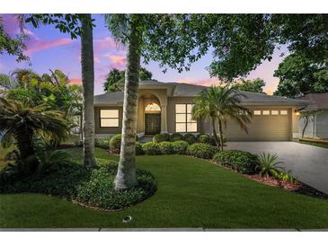 Charming single-story home featuring lush landscaping, a two-car garage, and a covered front entry at 1118 Captains Way, Tarpon Springs, FL 34689