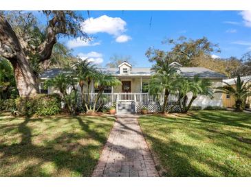 Charming single-story home with a brick walkway, palm trees, and a welcoming front porch at 13015 Elm St, Odessa, FL 33556
