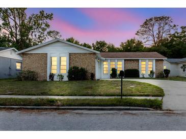 Charming single-story home with stone accents, lush landscaping, and well-lit windows at 3139 Corona Dr, Holiday, FL 34690