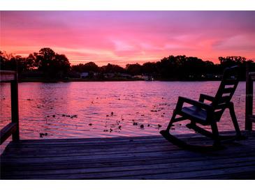 Beautiful pink sunset over a lake with a rocking chair sitting on the edge of a wooden dock at 3629 Lake Breeze Dr, Land O Lakes, FL 34639