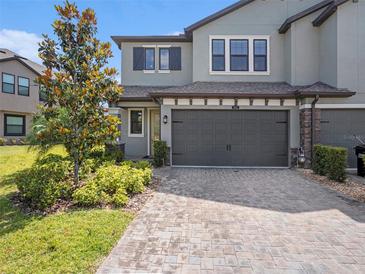 Charming home featuring a two-car garage, stone accents, and lush landscaping in a well-kept neighborhood at 4644 Almada Ln, Wesley Chapel, FL 33543