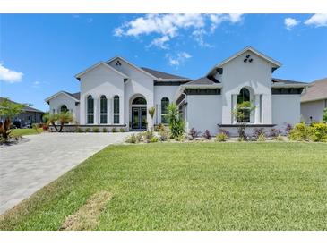 Stunning white home featuring lush landscaping and a paved driveway on a sunny day at 13539 Carryback Dr, Dade City, FL 33525