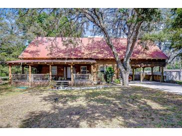 Charming log home with a metal roof, covered porch, and attached carport at 4126 Burrows Rd, Zephyrhills, FL 33542