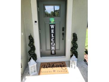 Charming front door with welcome mat, festive decor, and potted spiral topiary trees at 5131 Forum Blvd, Holiday, FL 34690