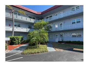 Three story condo building featuring a well maintained lawn with mature palm trees and tropical landscaping at 5660 80Th N St # A102, St Petersburg, FL 33709
