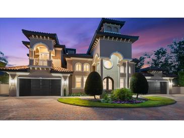 A luxurious home featuring a tower entry, arched windows, a balcony, multi-car garage, and an inviting driveway at 1600 Magnolia Rd, Belleair, FL 33756
