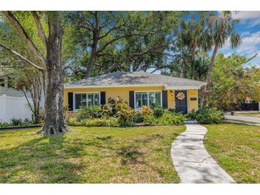 Charming yellow home with dark shutters, lovely landscaping, and a welcoming walkway leading to the front door at 4124 W San Juan St, Tampa, FL 33629