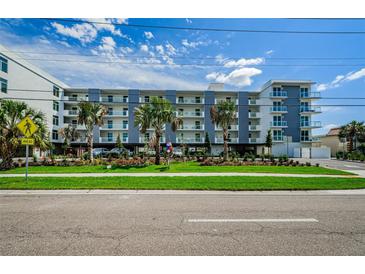 Modern condo building featuring well-kept landscaping, palm trees, and stylish architectural design at 415 Island Way # 511, Clearwater Beach, FL 33767