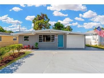 Charming single-story home featuring a light blue door, attached garage, and well-maintained landscaping at 4304 W Arch St, Tampa, FL 33607