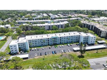 Expansive aerial view of a multi-story apartment building with ample parking surrounded by lush greenery at 5970 80Th Street North # 206, St Petersburg, FL 33709