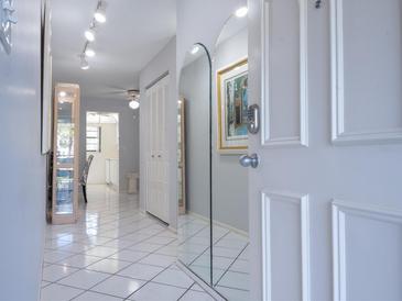 Bright hallway with white tile flooring and a large mirror to give the illusion of a bigger space at 5970 80Th Street North # 206, St Petersburg, FL 33709