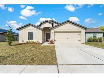 Charming single-story home with a well-manicured lawn and attached two-car garage under a sunny sky at 1102 Wynnmere Walk Ave, Ruskin, FL 33570