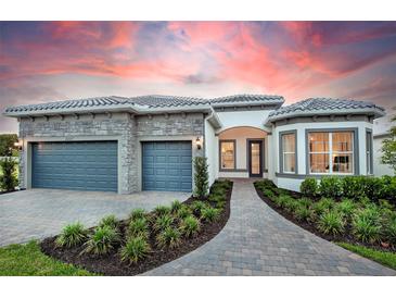 Beautiful home exterior with a lush landscaped yard, stone accents, a gray tiled roof, and a two-car garage at 1845 Ridgemore St, North Port, FL 34289