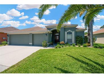 Charming single-story home featuring a well-manicured lawn, arched entryway, and a spacious three car garage at 2321 Wood Pointe Dr, Holiday, FL 34691