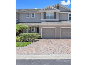Charming townhome featuring a two-car garage, neat landscaping, and a paved driveway at 26922 Juniper Bay Dr, Wesley Chapel, FL 33544