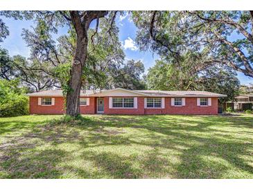Charming single-story brick home featuring a lush green lawn and mature trees at 37348 Tucker Rd, Zephyrhills, FL 33541