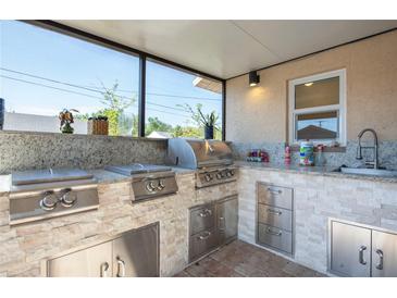 An outdoor kitchen with stainless steel appliances, granite countertops, and a built-in sink, perfect for entertaining at 6328 S Harold Ave, Tampa, FL 33616