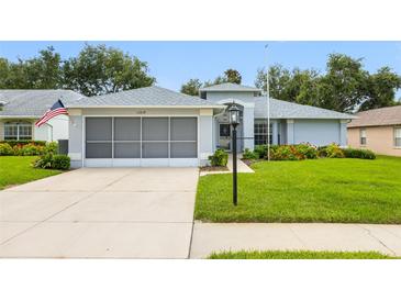 Charming single-story home featuring a screened garage, fresh landscaping and a well-manicured lawn at 11218 Sun Tree Rd, Hudson, FL 34667