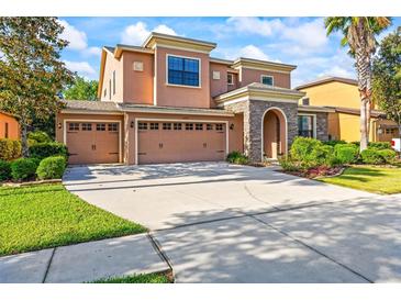 Attractive two-story home with a three-car garage, stone entrance, and well-manicured lawn and landscaping at 32718 Summerglade Dr, Wesley Chapel, FL 33545
