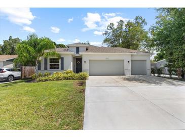 Charming single story home featuring a well-manicured lawn, a two car garage, and tropical landscaping at 3605 W Paxton Ave, Tampa, FL 33611