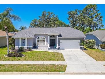 Beautiful single-story home featuring a well-manicured lawn, gray exterior paint and two-car garage on a sunny day at 4951 Musselshell Dr, New Port Richey, FL 34655