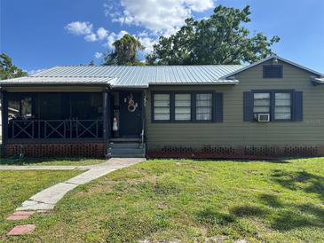 Charming home featuring a screened porch, metal roof, and updated landscaping on a sunny day at 707 E Patterson St, Tampa, FL 33604